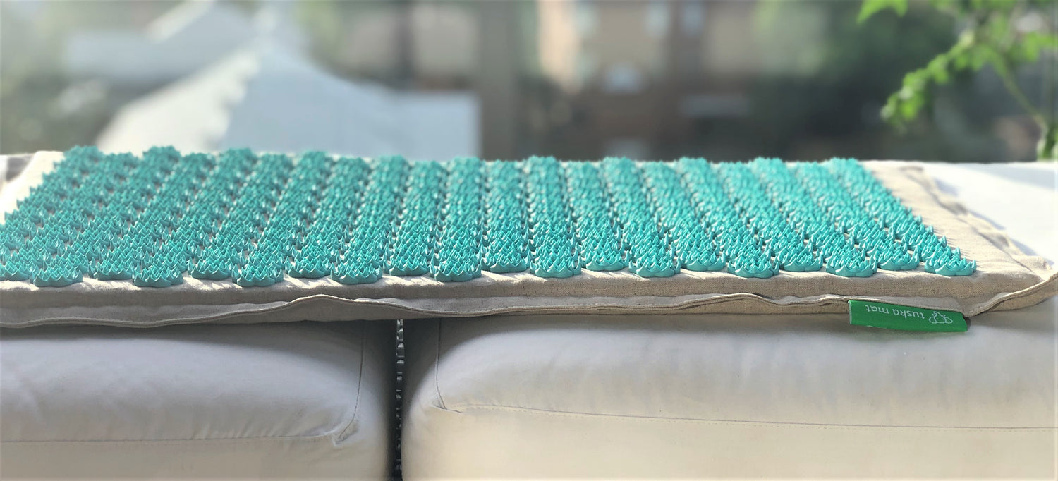 A blue acupressure mat on a couch outside